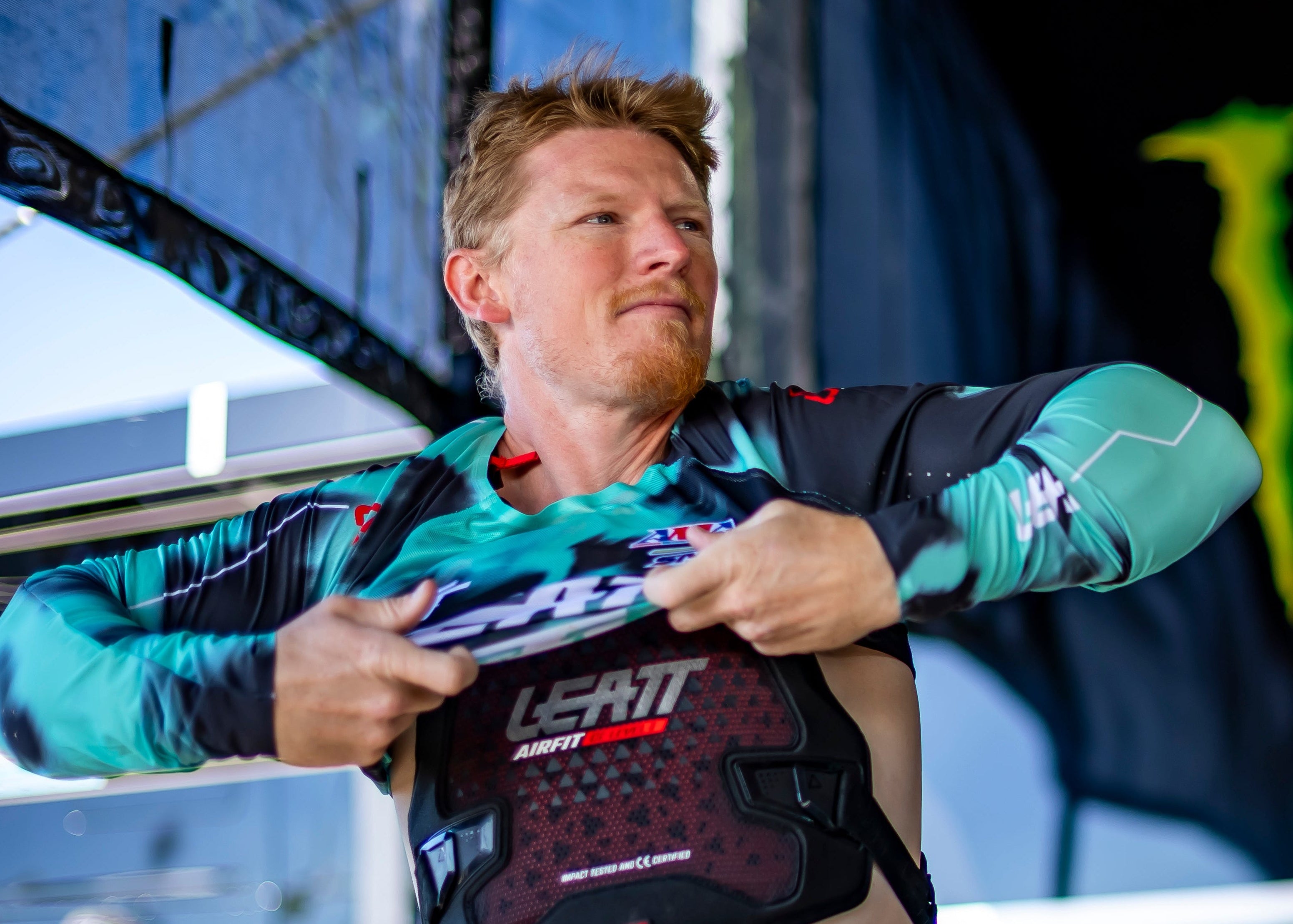Person preparing for a race with a Monster Energy branded backdrop